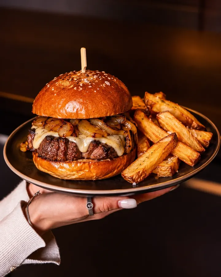 Dry Aged Waldblick Burger mit geschmolzenem Käse, gerösteten Zwiebeln und Steakhouse-Pommes