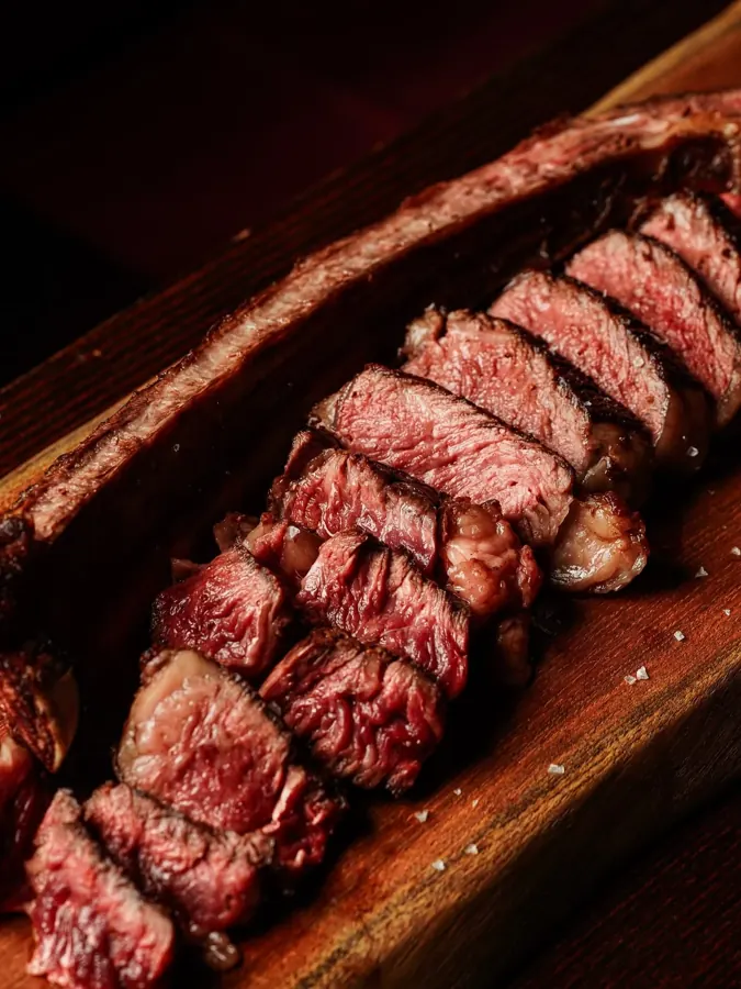 Aufgeschnittenes Tomahawk-Steak, medium rare, auf Holzbrett im Ristorante Waldblick